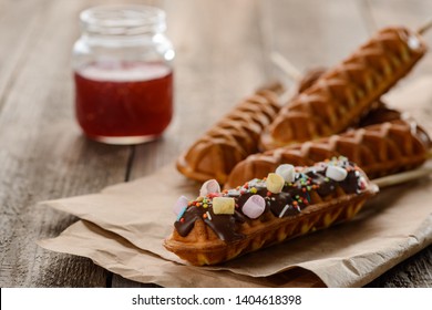 Delicious waffle pops with jam, selective focus. Decorated with chocolate glaze, colorful marshmallow and sprinkles. Confectionery trend.