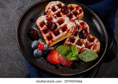 Delicious Waffles Heart Shape With  Powdered Sugar And Berries On Ceramic Black Plate On Grey Background. Top View. Sweet Meal. Dessert. Serving Food