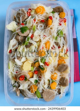 Delicious White Vermicelli served with various complement, meatballs, carrots, and green vegetables. Homemade cuisine on clear container. Indonesia - Jakarta, January 2024.