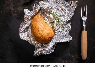 Delicious Whole Jacket Baked Potato Lying On Its Crumpled Silver Aluminium Foil Wrapper Fresh Off The Summer Barbecue, Overhead View