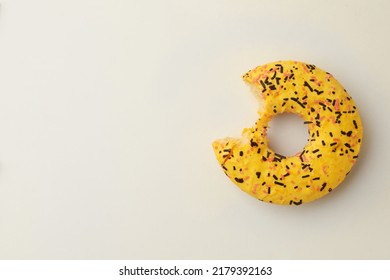 Delicious Yellow Glazed Donut With Bite Mark On White Background, Top View. Space For Text