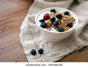 Delicious yogurt breakfast bowl with muesli and fresh blackberries on a wooden table and linen kitchen-towel. Healthy and organic nutrition concept. Blackberry and raspberry muesli. Yogurt in a bowl  - Powered by Shutterstock