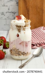 Delicious Yogurt, Strawberry, Banana And Granola Parfait On An Old Wooden Countertop