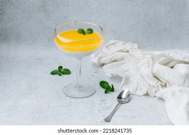 Delicious Yougurt Topped With Jelly In A Glass Decorated With Mint Leaf. Next To It Tea Spoon And Piece Of Cloth On A Table.