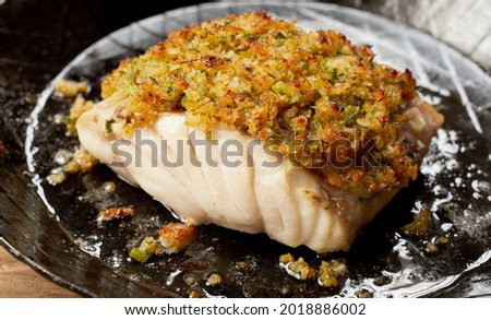 Delicious yummy baked cod fish fillet with coating breadcrumbs served on ceramic plate