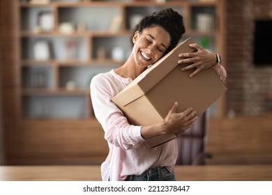 Delighted attractive young woman customer hugging paper box parcel with closed eyes and smiling, home office interior, copy space. Parcel mail delivery, courier service concept - Shutterstock ID 2212378447