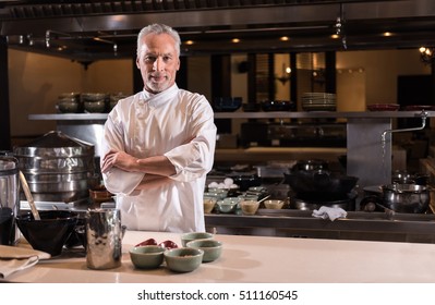 Delighted bearded chef standing in the kitchen of the restaurant - Powered by Shutterstock