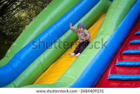 Delighted boy rides down a large inflatable rubber slide