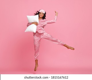 Delighted ethnic woman in sleepwear smiling and leaping up while having fun against pink backdrop - Shutterstock ID 1815167612