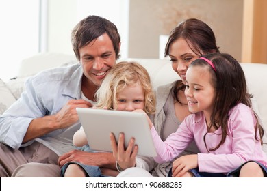 Delighted Family Using A Tablet Computer In A Living Room