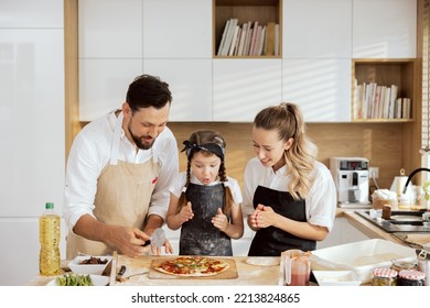 Delighted father and mother putting out homemade pizza putting on wooden surface. Surprised delighted kid looking at pizza. Happy family baking cooking having fun spending time together. - Powered by Shutterstock