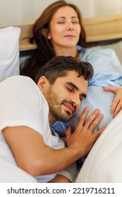 Delighted Father Tenderly Lie Down On Belly Of Beloved Pregnant Wife On Bed To Feel And Hear Unborn Baby Kicking In Stomach. Man As Fatherhood Happy For Maternity Care And Expecting For Child Birth.