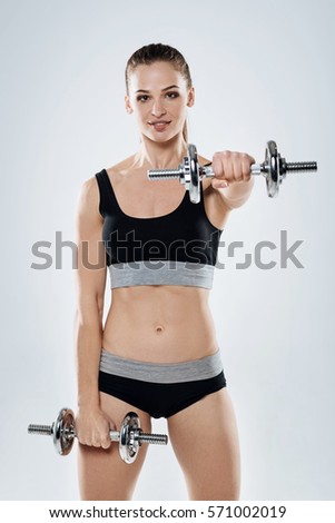 Similar – One young athletic woman at crossfit training, exercising with trx suspension fitness straps over dark background, front view, looking at camera