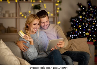 Delighted husband and wife making purchases online, using digital tablet and credit card, Christmas atmosphere at home. Happy young family shopping online on pad, using Christmas offers, copy space - Powered by Shutterstock