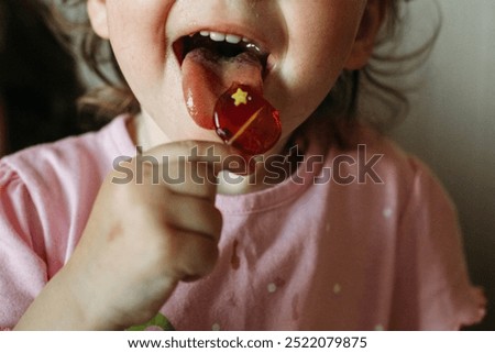 Similar – Image, Stock Photo Young child savoring a blue lollipop enthusiastically