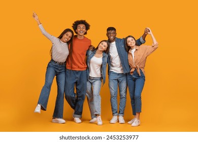 A delighted multiethnic team celebrates together with embraces, portraying the zest of multiethnic friendship on an isolated orange background - Powered by Shutterstock