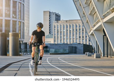 Delighted Professional Female Cyclist In Black Cycling Garment And Protective Gear Smiling, Looking Satisfied With Her Training Outdoors On A Sunny Day