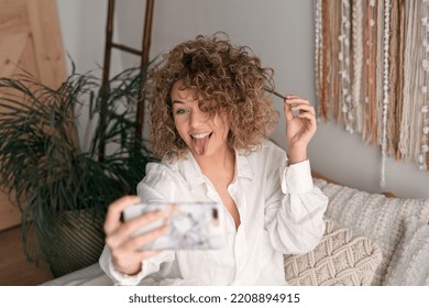 Delighted Woman Showing Tongue And Taking Self Shot At Home