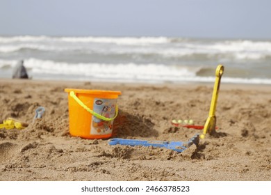 A delightful collection of children's beach toys, including a bucket and various tools, perfect for building sandcastles by the seaside. - Powered by Shutterstock