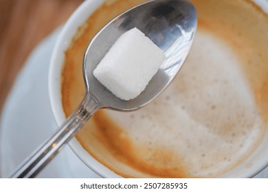 A delightful cup of aromatic espresso with a sugar cube placed on a spoon above it for sweetness - Powered by Shutterstock