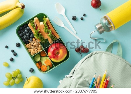 A delightful and nourishing school lunch from bird's eye top view. A lunchbox containing delicious sandwiches, accompanied by a water bottle and backpack on blue background with space for text or ad