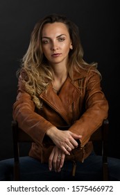 A delightful young woman with long blonde hair in a light brown leather jacket