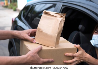 Deliver Guy Bring Box Brown Reusable Paper Grocery Bag To Woman Driver Wearing Surgical Mask Car Open Window Driving Thru Pickup Food Social Distancing Requirements Home Delivery At Pandemic Concept