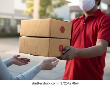 Deliver Man Wearing Face Mask In Red Uniform Handling Bag And  Parcel Box Give To Female Costumer Postman And Express Grocery Delivery Service During Covid19.