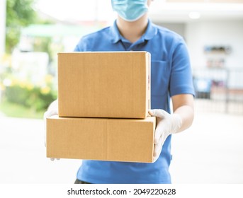 Deliver Man Wearing Medical Gloves And Face Mask In Blue Uniform Handling Parcel Box Give To Female Costumer Postman And Express Grocery Delivery Service During Covid19.