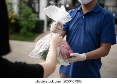 Deliver Man Wearing Medical Gloves And Face Mask In Blue Uniform Handling Bag Of Fruits And Vegetables  Give To Female Costumer Postman And Express Grocery Delivery Service During Covid19.