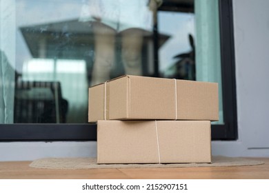 Deliver parcels box on door mat near home entrance door. Delivery online order to home - Shutterstock ID 2152907151