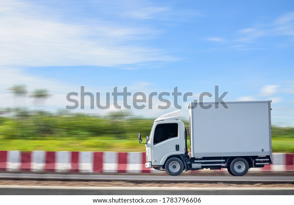 Deliver a small white truck moving on a\
green natural path against a blue sky\
background.
