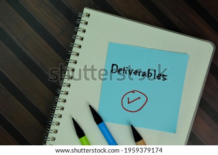 Deliverables write on sticky notes isolated on Wooden Table. Selective focus on Deliverables text