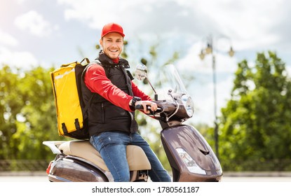 Delivering Food. Courier Man With Yellow Backpack Sitting On Moto Scooter Smiling To Camera Outside. Free Space