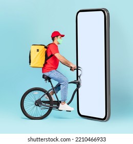 Delivery Application. Courier Guy On Bike Riding Into Huge Cellphone With Blank Screen Over Blue Studio Background. Deliveryman Delivering Food. Square Shot, Mockup