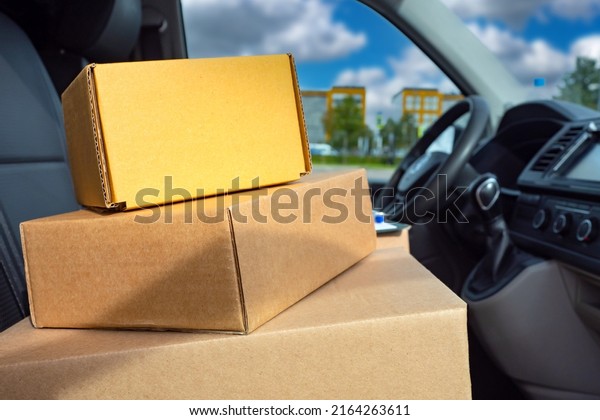 delivery box\
next to steering wheel. Cardboard delivery box in car. Courier van\
inside view. Delivery box close up. Concept - courier logistics of\
goods. Transportation of parcels by\
van.