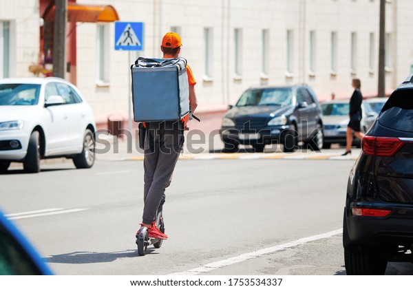 Delivery boy on e-scooter with backpack\
dangerous driving along the road among cars. Delivery service from\
cafes and restaurants. Courier delivering food on electric scooter.\
supply food to\
customers