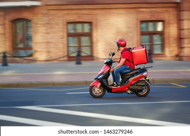 Delivery boy of takeaway on scooter with isothermal food case box driving fast. Express food delivery service from cafes and restaurants. Courier on the moto scooter delivering food. - Shutterstock ID 1463279246