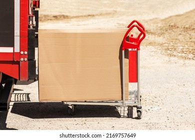 Delivery Carrying Cardboard Box In Hand Truck Trolley From Van. Delivery Parcel To Any Place Any Time. Post Service