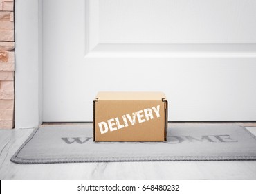 Delivery Concept. Cardboard Box On Rug At Door