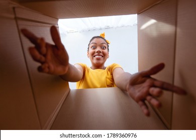 Delivery Concept. Excited African Woman Unpacking, Opening Carton Box And Trying To Get Something, View From The Inside