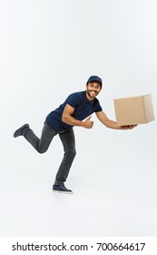 Delivery Concept - Handsome African American Delivery Man Rush Running For Delivering A Package For Customer. Isolated On Grey Studio Background. Copy Space.