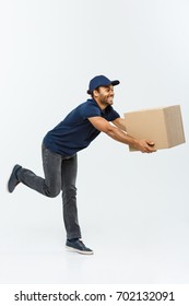 Delivery Concept - Handsome African American Delivery Man Rush Running For Delivering A Package For Customer. Isolated On Grey Studio Background. Copy Space.