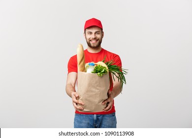 Delivery Concept - Handsome Cacasian delivery man carrying package bag of grocery food and drink from store. Isolated on Grey studio Background. Copy Space.