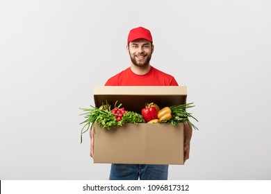 Delivery Concept: Handsome Caucasian Grocery Delivery Courier Man In Red Uniform With Grocery Box With Fresh Fruit And Vegetable