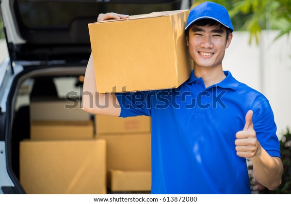 Delivery concept - postman in blue uniform\
holding package