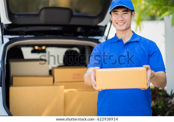 Delivery concept - postman in blue uniform\
holding package