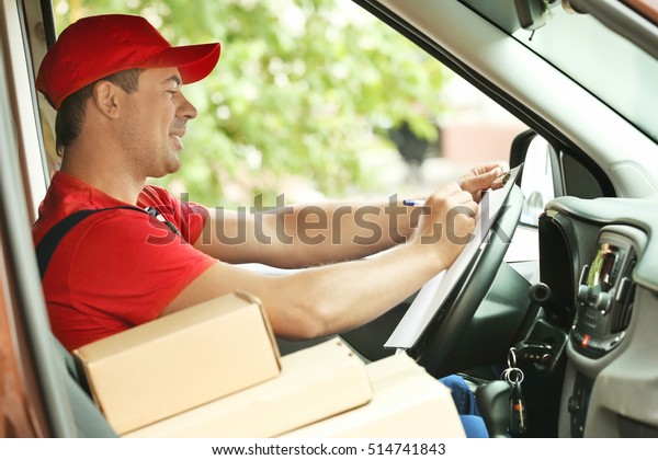Delivery\
concept. Postman checking orders in a\
car