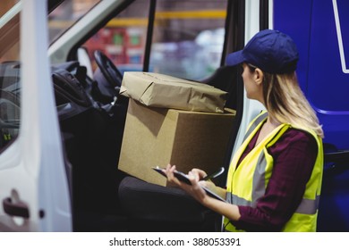 Delivery driver checking his list on clipboard in a large warehouse