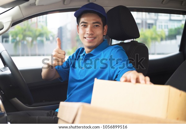Delivery driver driving car with packages on\
seat outside the\
warehouse\
